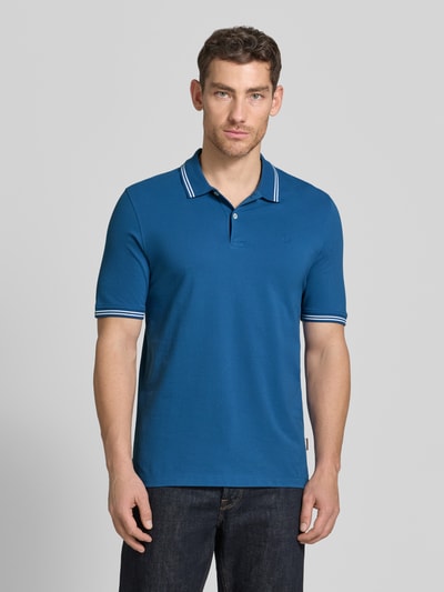Männermodel trägt Regular Fit Poloshirt mit Logo-Stitching von bugatti in Blau aus Reine Baumwolle, Polokragen, Kurze Knopfleiste, Label-Detail, Ganzkörperansicht von vorne.