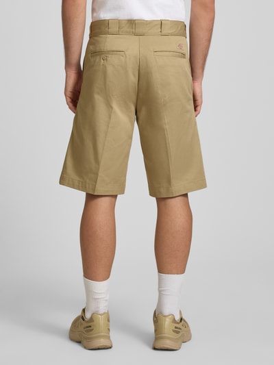 Männermodel trägt Bermudas mit französischen Eingrifftaschen von Dickies aus Reine Baumwolle in Beige, Straight Fit, Knopf-Reißverschluss, Bundweite 42 cm, Innenbeinlänge 31 cm, Gesäßtaschen, Ganzkörperansicht Rückansicht.