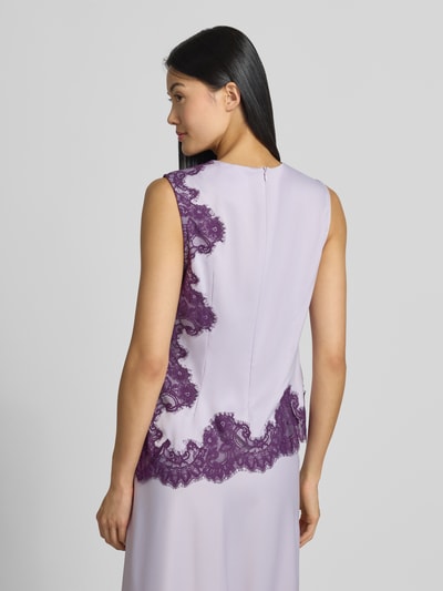 Frauenmodel trägt Top mit Spitzenbesatz Modell 'PELLA' von YAS in Flieder mit violetter Spitze, asymmetrische Form, Material-Mix, Ganzkörperansicht Rückansicht.