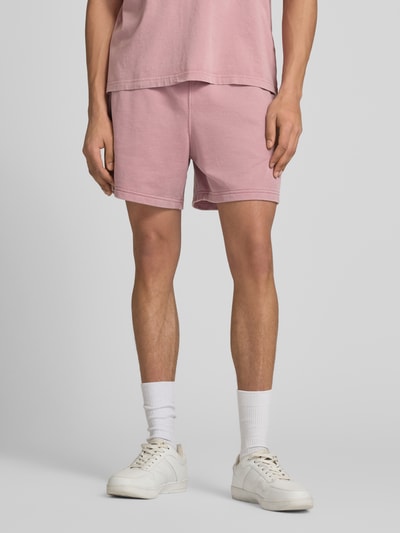 Männermodel trägt Sweatshorts mit Eingrifftaschen von CHAMPION in Rosa, Baumwoll-Mix, Regular Fit, Nahaufnahme Unterkörper, Vorderansicht.