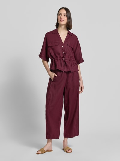 Frauenmodel trägt Leinenhose in verkürzter Passform mit elastischem Bund von Christian Berg Woman, bordeauxfarben, Wide Leg, Ganzkörperansicht von vorne.
