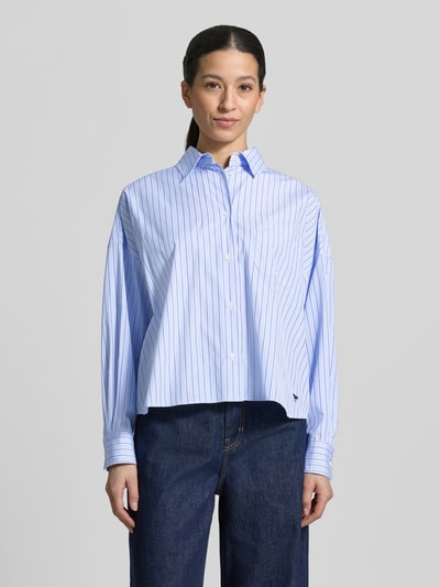 Frauenmodel trägt Oversized Hemdbluse aus reiner Baumwolle Modell 'AUREO' von Weekend Max Mara, blau-weiß gestreift, Logo-Stitching, Ganzkörperansicht von vorne.
