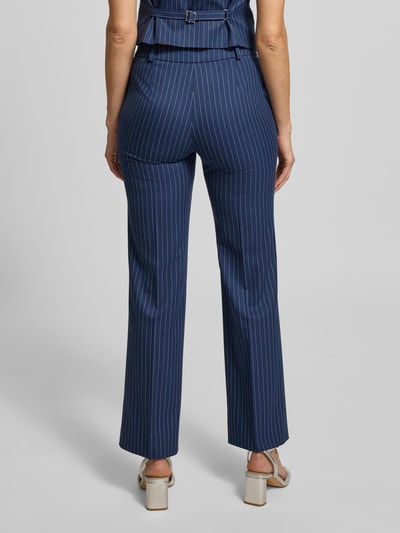 Frauenmodel trägt Regular Fit Anzughose mit Viskose-Anteil Modell 'HILANDO' von HUGO in Blau mit feinen weißen Streifen, unifarbene Optik, seitliche Eingrifftaschen, Gürtelschlaufen, Label Stitching, Ganzkörperansicht Rückansicht.