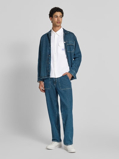 Męskimodel nosi Oversized Freizeithemd aus reiner Baumwolle Modell 'EKYNONE' von HUGO, jednokolorowy, splot twill, koszula casualowa, krój oversized, kołnierzyk typu kent, na całej długości listwa guzikowa, naszywka z logo, pas na plecach, długi rękaw, sportowe mankiety, nakładane kieszenie na piersi, bawełna, Ganzkörperansicht von vorne.