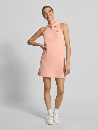 Kobiece model prezentuje Slim Fit Polokleid aus Baumwoll-Mix od Lacoste Sport, jasnoróżowy, krój slim fit, mini, piqué, logo, widok z przodu pełna sylwetka.