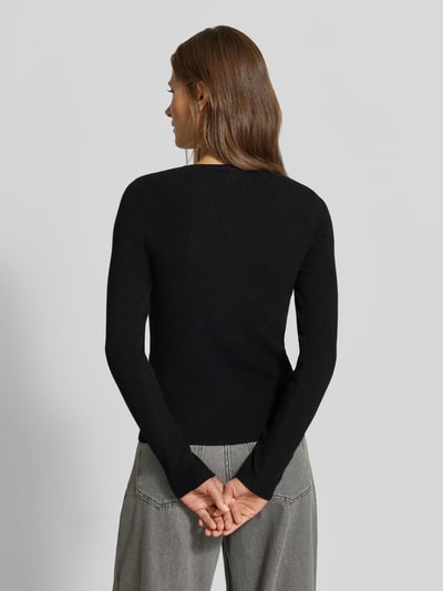 Frauenmodel trägt Slim Fit Longsleeve in Strick-Optik von MYON, schwarz, feine Struktur, Henley-Ausschnitt, Ganzkörperansicht Rückansicht.