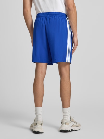 Männermodel trägt Regular Fit Sport-Shorts mit Tunnelzug von adidas Sportswear, Optik: Unifarben, Kontraststreifen, Ganzkörperansicht Rückansicht.
