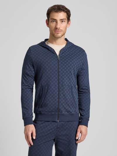 Männermodel trägt Sweatjacke mit Logo-Muster und Kapuze von JOOP! Collection in Dunkelblau, Reine Baumwolle, Regular-Fit, Ganzkörperansicht von vorne.