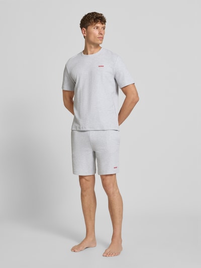 Männermodel trägt Regular Fit Sweatshorts aus Baumwoll-Mix Modell 'AUSTIN' von HUGO in Hellgrau, Herren Sweatshorts, Ganzkörperansicht von vorne.