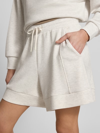 Frauenmodel trägt Shorts mit elastischem Bund Modell 'alder' von VARLEY aus Viskose-Mix mit Stretch-Anteil, High-Rise-Fit, Kordelzug, Bundweite bei Größe S 42 cm, Innenbeinlänge 14 cm, heller Stoff mit glatter Struktur, Nahaufnahme Oberkörper.
