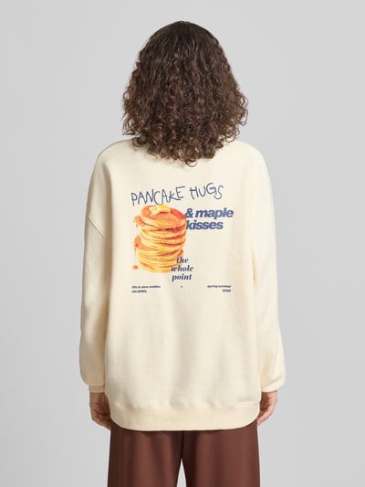 Kobiece model nosi Oversized Sweatshirt mit Logo-Stitching Modell 'Pancake' od OH APRIL z mieszanki bawełny, kremowy kolor, krój oversized fit, okrągły dekolt, elastyczne wykończenia, nadruk i wyhaftowane logo na plecach, widok całej sylwetki od tyłu.
