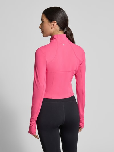 Frauenmodel trägt Slim Fit Jacke mit Stehkragen Modell 'Storm' von Fabletics in Pink, Cropped Fit, Daumenschlaufen, Ganzkörperansicht Rückansicht.
