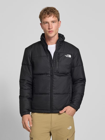 Männermodel trägt Regular Fit Jacke in Stepp-Optik Modell 'NUKETO' von The North Face, Schwarz, Logo-Print, Ganzkörperansicht von vorne. Herren Jacke mit Stehkragen und Napoleontasche, Rückenlänge 69 cm, Schulterbreite 46 cm, Brustweite 55 cm, Ärmellänge 64 cm.