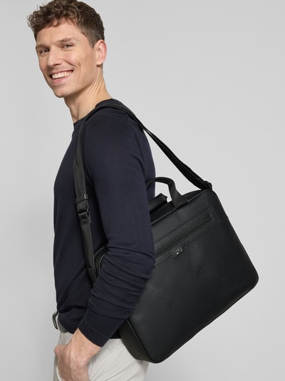 Männermodel trägt Laptoptasche mit Label-Applikation Modell 'LEWIS_DOC CASE' von BOSS aus schwarzem, genarbtem Leder, Ganzkörperansicht von vorne.