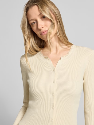 Frauenmodel trägt Slim Fit Strickjacke aus Viskose-Mix Modell 'WONDER' von Vero Moda, Optik: Unifarben, Spitzen-Besatz, Rundhals, Ärmelform: Langarm, Materialverarbeitung: Rippstrick; Nahaufnahme Oberkörper.