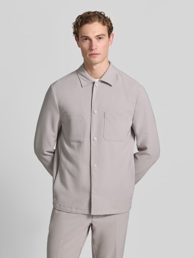 Männermodel trägt Regular Fit Overshirt mit Brusttaschen von MCNEAL in hellem Grau, Material-Mix mit Stretch-Anteil, Kentkragen, Druckknopfverschluss, Sportmanschetten, Rückenlänge bei Größe M: 73 cm, Ganzkörperansicht von vorne.