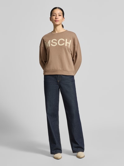 Modelka nosi Sweatshirt mit überschnittenen Schultern od MSCH Copenhagen, bawełniany miks, prosty krój, beżowy kolor, widok całej sylwetki z przodu