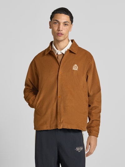 Männermodel trägt Loose Fit Bomberjacke aus reiner Baumwolle von Nike in Braun, strukturierte Oberfläche, Ganzkörperansicht von vorne. Herren Bomberjacke / Blouson
