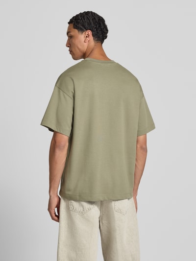 Männermodel trägt Herren T-Shirt mit Rundhalsausschnitt Modell 'BARRON' von Jack & Jones, Baumwoll-Mix mit Stretch-Anteil, Relaxed-Fit, Rückenlänge bei Größe M 73 cm, dezentes Beige, glatte Textur, Ganzkörperansicht Rückansicht.