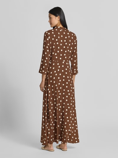 Frauenmodel trägt Hemdblusenkleid aus Leinen Modell 'SAVANNA' von YAS mit weißen Punkten, A-Linie, Maxilänge, Ganzkörperansicht Rückansicht.