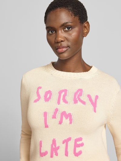 Frauenmodel trägt Regular Fit Strickpullover aus reiner Baumwolle Modell 'MCOEROSO' von MAX&Co., beige mit pinkem Schriftzug, Nahaufnahme Oberkörper, Damen Strickpullover von MAX&Co.