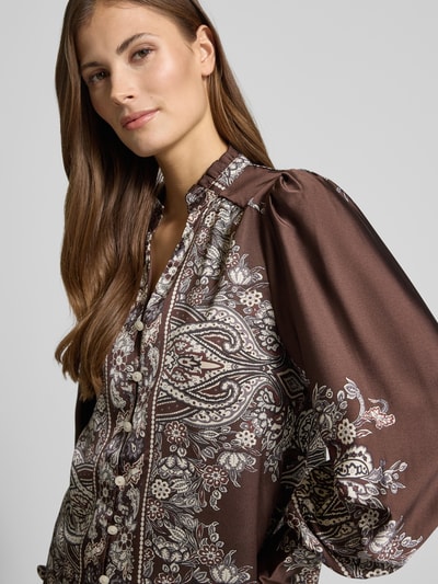 Frauenmodel trägt Relaxed Fit Bluse mit Allover-Paisley-Print Modell 'Massima' von Neo Noir in Braun mit Satin, Stehkragen, Rüschenbesatz, durchgehender Knopfleiste, V-Ausschnitt, langärmelig und Ärmelabschlüsse, Nahaufnahme Oberkörper.