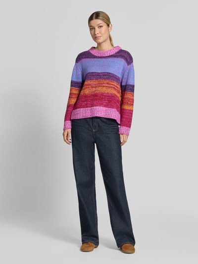 Frauenmodel trägt Strickpullover mit Rundhalsausschnitt Modell 'ALINEA' von ICHI im Baumwoll-Mix, Grobstrick, farbenfroh gestreift, Loose Fit, kombiniert mit weiter Jeans, Ganzkörperansicht von vorne.