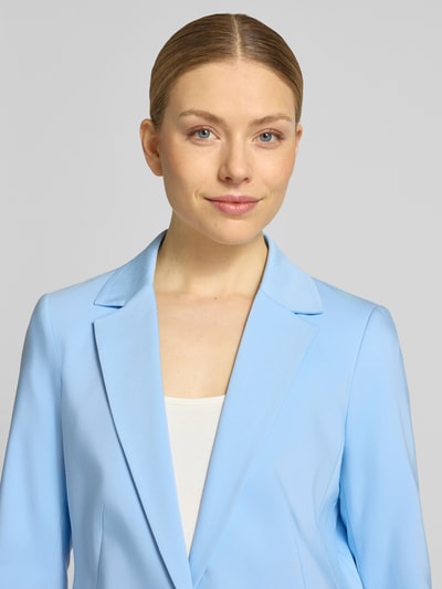 Kobiece modelka nosi Blazer mit Reverskragen und Pattentaschen od comma, mieszanka bawełny z dodatkiem streczu, prosty krój, kołnierz z połami, zapięcie na guzik, kieszenie z patką, długość tyłu w rozmiarze 36: 69 cm, szerokość w rozmiarze 36: 46 cm, długość rękawów w rozmiarze 36: 61 cm, jasnoniebieski kolor, gładka tekstura, zbliżenie na górną część ciała