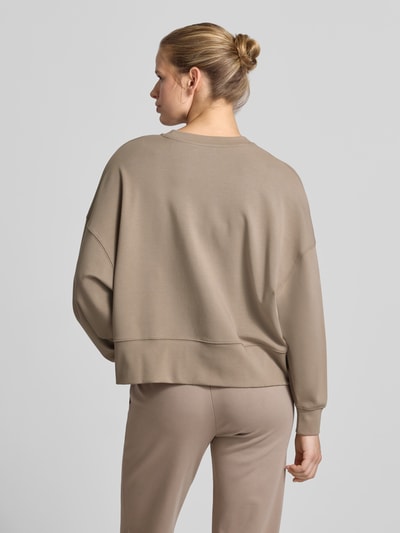 Frauenmodel trägt Oversized Sweatshirt mit breitem Bund von Juvia in Beige, lockerer Schnitt, Baumwoll-Modal-Mix, Rückenansicht Ganzkörperansicht.