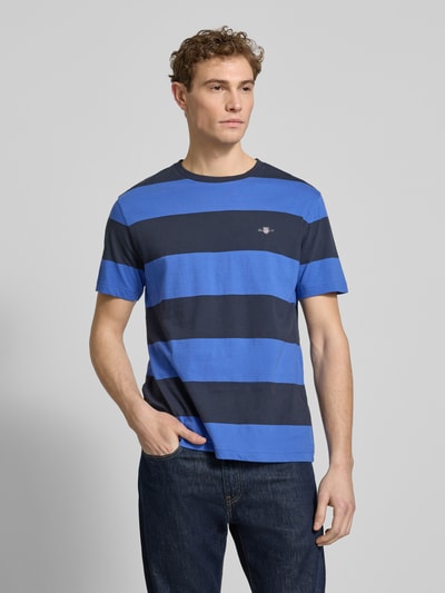 Männermodel trägt Regular Fit T-Shirt mit Logo-Print Modell 'BAR' von Gant in Blau mit breiten Streifen aus reiner Baumwolle, Nahaufnahme Oberkörper.