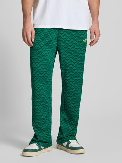 Männermodel trägt grüne Sweatpants mit elastischem Bund von adidas Originals, lockerer Schnitt, Eingrifftaschen, Label-Stitching, Nahaufnahme Unterkörper.