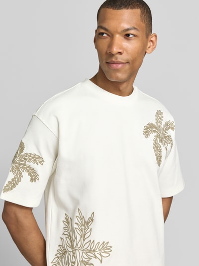 Männermodel trägt T-Shirt mit Motiv-Stitching von JAKE*S STUDIO MEN, weiß mit goldfarbenem Muster, Baumwoll-Mix und Rundhals, Nahaufnahme Oberkörper.