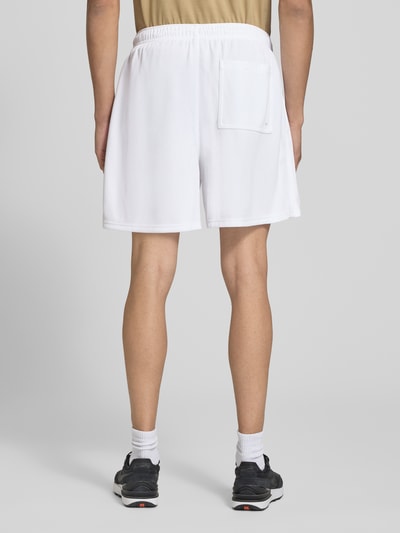 Männermodel trägt Loose Fit Sportshorts mit Tunnelzug Modell 'Club Mesh' von Nike, weiß, strukturierte Oberfläche, Ganzkörperansicht Rückansicht, Herren Sportshorts von Nike.
