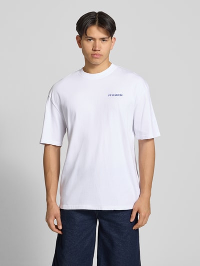 Männermodel trägt Oversized Herren T-Shirt mit Rundhalsausschnitt Modell 'Frombork' von Pegador, Reine Baumwolle, 1/2-Arm, Logo-Detail, Rückenlänge 71 cm, Ganzkörperansicht von vorne.