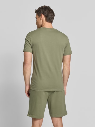 Männermodel trägt Regular Fit T-Shirt aus reiner Baumwolle von Lacoste in Optik: Unifarben, Label-Applikation, Ganzkörperansicht Rückansicht.