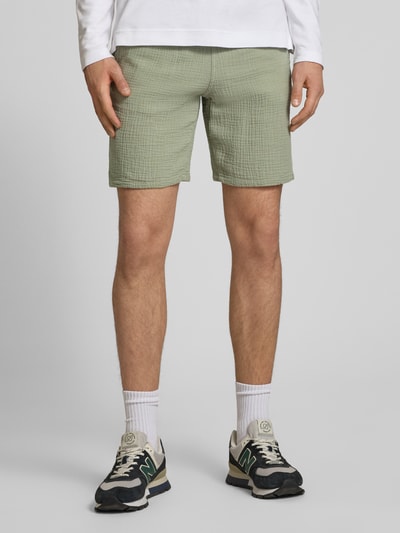 Männermodel trägt Shorts mit structuurpatroon model 'AIDEN' van Jack & Jones in lichtgroen, katoenmix, straight fit, steekzakken, elastische band met trekkoord, bandwijdte maat M 40cm, binnenbeenlengte 21cm, detailopname benen, Ganzkörperansicht von vorne.