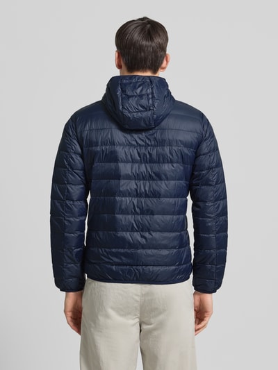 Męski model nosi Kurtka puchowa z zamkiem błyskawicznym od Armani, krój regular fit, kaptur, nadruk z logo, kieszenie z wszytym zamkiem, całkowita długość tyłu 68 cm, szerokość ramion 44 cm, szerokość klatki piersiowej 52 cm, długość rękawa 61 cm, widok na całą sylwetkę z tyłu.