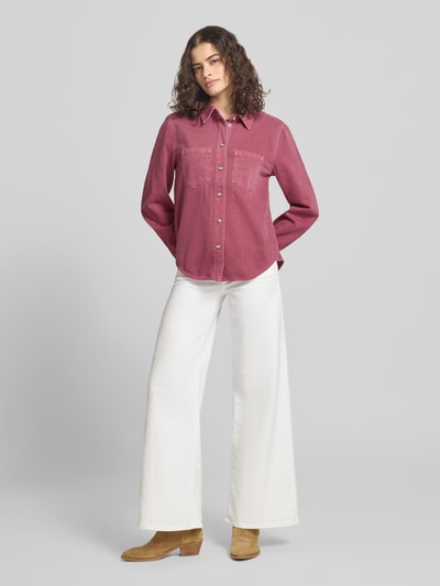 Modelka nosi Regular Fit Jeansbluse aus reiner Baumwolle Modell 'SILLA' od Only, bordowy denim, długie rękawy, kieszenie, całkowity widok z przodu.