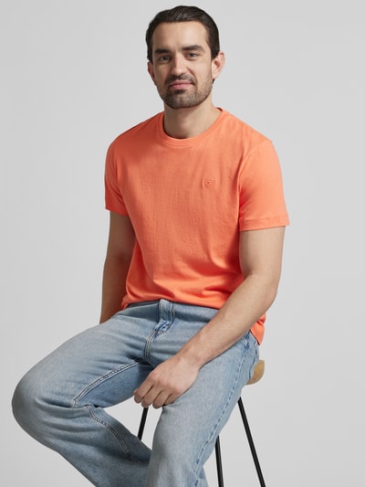 Männermodel trägt Regular Fit T-Shirt aus reiner Baumwolle von Tom Tailor in Uni-Orange mit Logo-Stitching, Rundhals, Kurzarm; Nahaufnahme Oberkörper.