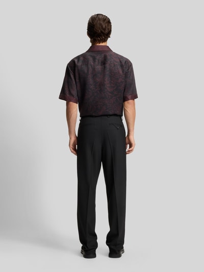 Männermodel trägt Regular Fit Anzughose mit Bügelfalten Modell 'FLIPS251X' von HUGO in Schwarz, Stretch-Twill, Ganzkörperansicht Rückansicht.