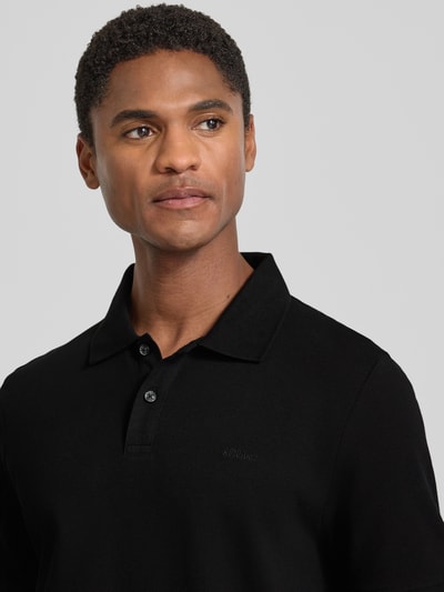 Männermodel trägt Regular Fit Poloshirt aus reiner Baumwolle von s.Oliver RED LABEL in Schwarz, Nahaufnahme Oberkörper.