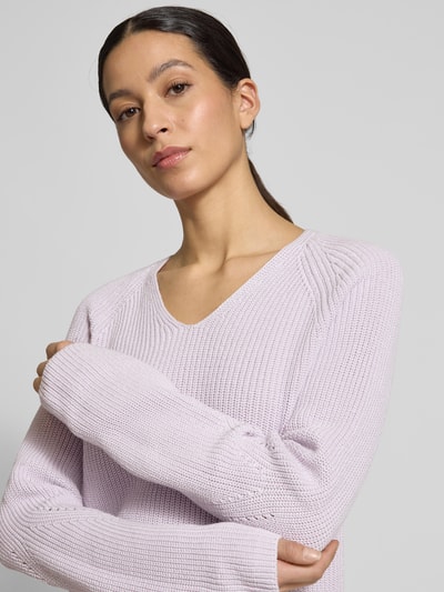 Frauenmodel trägt Regular Fit Strickpullover aus reiner Baumwolle Modell 'C_FARDELLINA' von BOSS Orange in Hellviolett, unifarben, mit V-Ausschnitt sowie langen Ärmeln, Strickstruktur gut erkennbar, Label-Applikation dezent, Nahaufnahme Oberkörper.