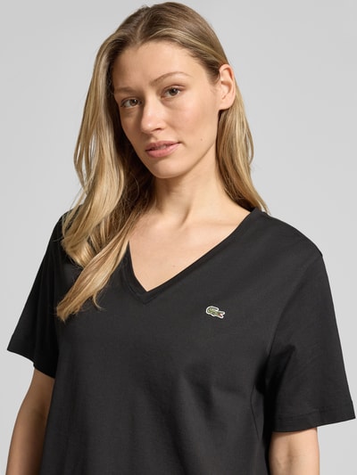 Frauenmodel trägt Relaxed Fit T-Shirt aus reiner Baumwolle von Lacoste, unifarben, V-Ausschnitt, Logo-Stitching, Nahaufnahme Oberkörper.
