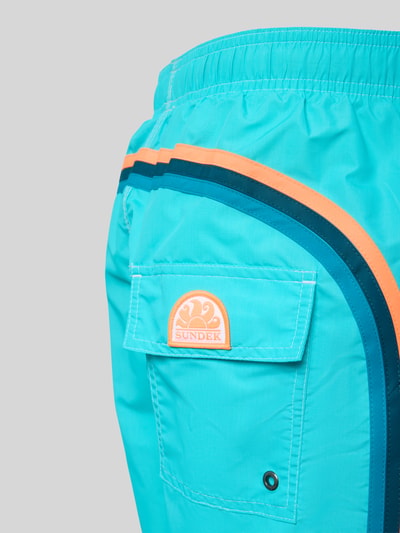Produktfoto, Badehose mit elastischem Bund Modell 'UNI SHORTS NEON' von Sundek in Türkis mit blauen und orangenen Streifen, Tunnelzug, Stoffstruktur sichtbar.