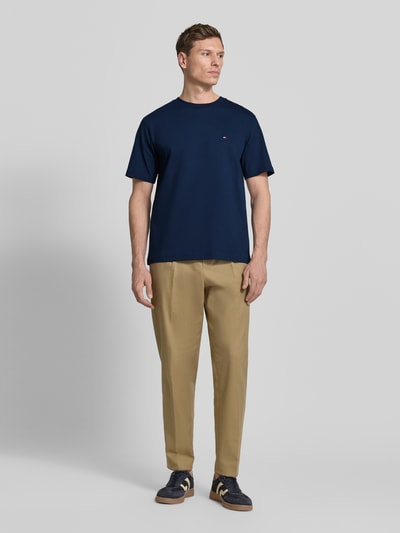 Männermodel trägt Relaxed Fit T-Shirt aus reiner Baumwolle von Tommy Hilfiger in Dunkelblau, unifarben, mit Logo-Stitching, Rundhals, Kurzarm, Ganzkörperansicht von vorne.