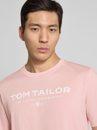 Männermodel trägt Regular Fit T-Shirt aus reiner Baumwolle von Tom Tailor in effen lichtroze, labelprint, ronde hals, uniseks katoen, Nahaufnahme Oberkörper.