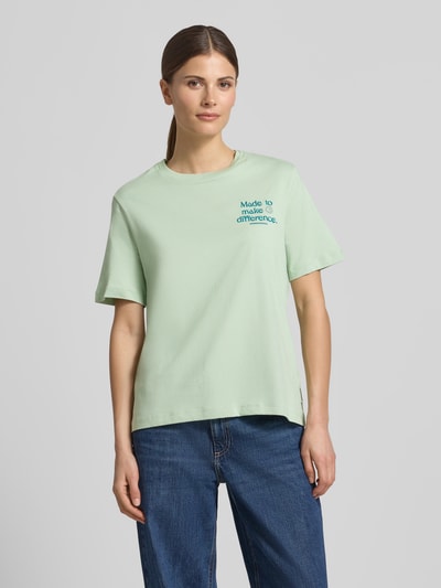 Vrouwenmodel draagt Regular Fit T-shirt uit puur biologisch katoen model 'LUALAA' van Armedangels, look: effen, ronde hals, korte mouw, jersey, labelpatch, logostitching, kleur lichtgroen, materiaalverwerking jersey, voorkant bovenlichaam close-up.