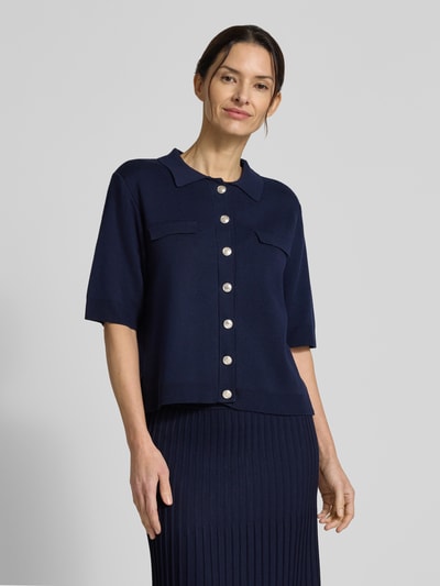 Modelka nosi kardigan rozpinany 'Strickjacke aus Viskose-Elasthan-Mix mit 1/2-Arm' od Milano Italy, mieszanka wiskozy i elastanu, krój slim fit, okrągły dekolt, listwa guzikowa, rękaw o dł. 1/2, długość tyłu w rozmiarze S: 55 cm, długość rękawów w rozmiarze S: 30 cm, ciemnogranatowy, widok całej sylwetki od przodu.