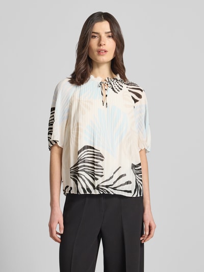 Kobiece modelka nosi Regular Fit Blusenshirt in Plissee-Optik od s.Oliver BLACK LABEL, wzór allover, krój regular fit, krótki rękaw, rzędy plisów, rysunek liści w kolorach beżu, błękitu i czerni, rüschenkragen, okrągły dekolt ze sznurkiem, gładka faktura, całkowity widok z przodu.
