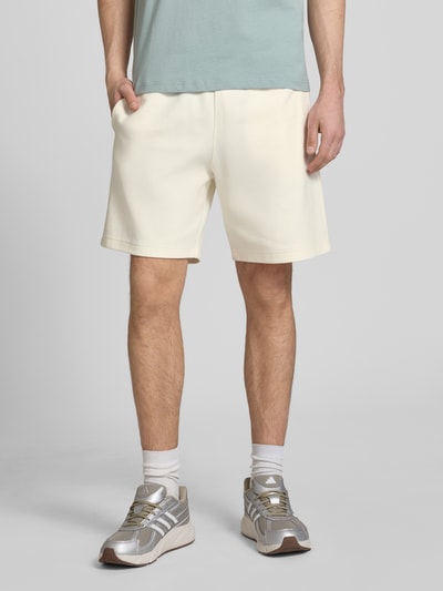 Mężczyznamodel nosi Shorts mit Label-Stitching mit elastischem Bund von CHAMPION, bawełna, krój regular fit, szerokość w rozmiarze M 37 cm, długość nogawki wewnętrznej 42 cm, widok całej sylwetki z przodu.